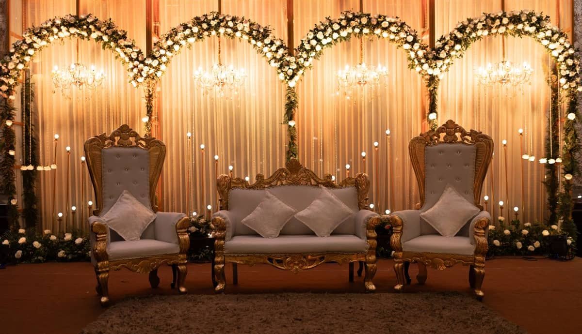 Gold-framed sofas on a floral stage with chandeliers and soft drapes behind